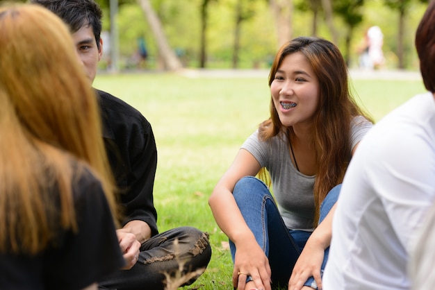 Grupo de jóvenes amigos asiáticos pasar el rato y relajarse juntos en el parque al aire libre