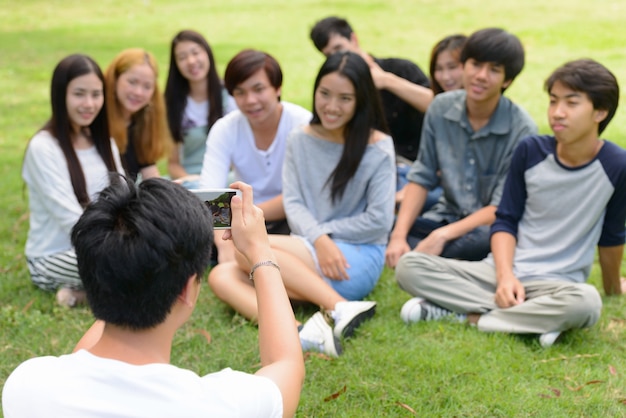 Grupo de jóvenes amigos asiáticos pasar el rato y relajarse juntos en el parque al aire libre