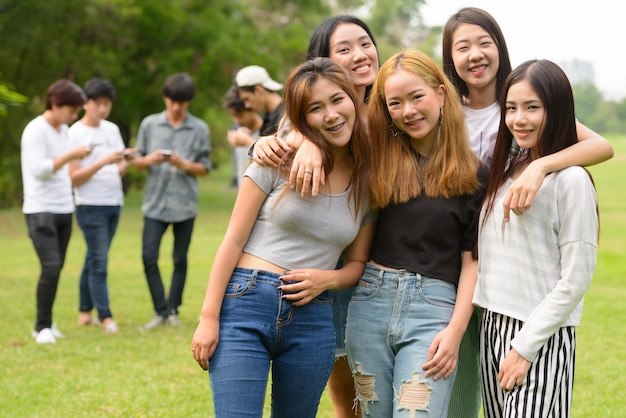 Grupo de jóvenes amigos asiáticos pasar el rato y relajarse juntos en el parque al aire libre