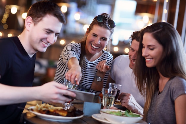 Grupo de jóvenes amigos disfrutando de la comida en el restaurante