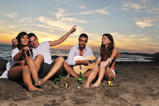 un grupo de jóvenes amigos felices se divierten y celebran mientras saltan y corren en la playa al atardecer