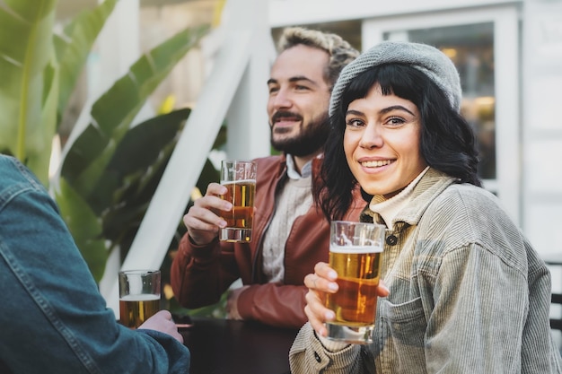 Grupo de jóvenes amigos hablando despreocupados sosteniendo vasos de cerveza sentados en el quiosco bar estilo de vida al aire libre concepto de amistad de personas y juventud alegre