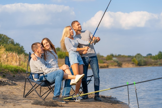 Grupo de jóvenes amigos pescando en el muelle junto al lago