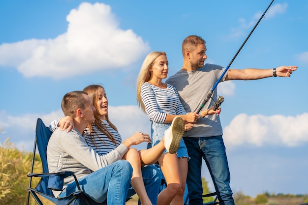 Grupo de jóvenes amigos pescando en el muelle junto al lago