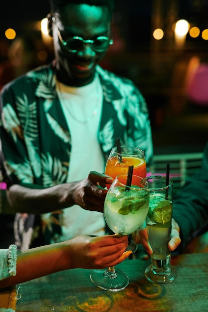 Grupo de jóvenes amigos reunidos en barra de bar con cócteles