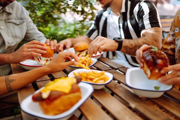 Grupo de jóvenes amigos reunidos en un café comiendo hamburguesas frescas y sabrosas Comida rápida Gente