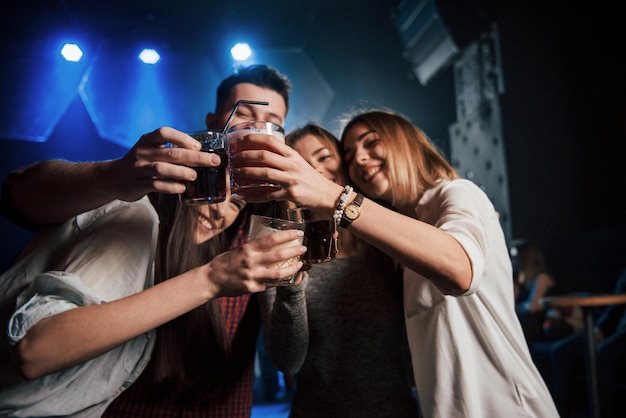 Un grupo de jóvenes amigos sonriendo y haciendo un brindis en el club nocturno