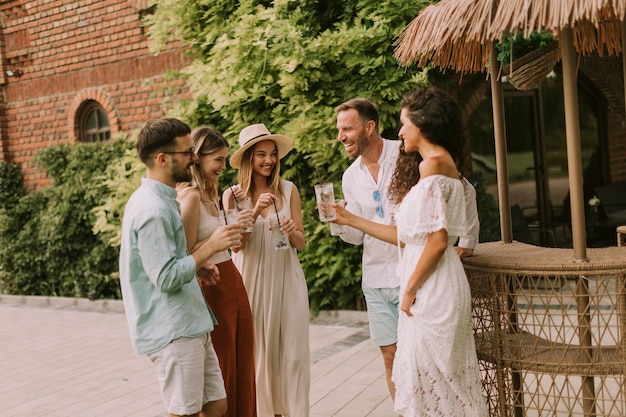 Grupo de jóvenes animando y divirtiéndose al aire libre con bebidas