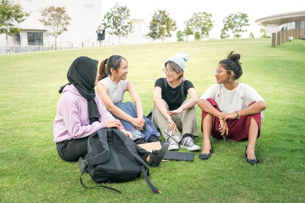 Grupo de jóvenes asiáticas sentadas en el césped verde y charlando