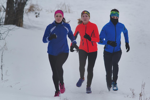 Foto grupo de jóvenes atletas corriendo técnicamente en bosque de invierno, concepto de deporte y ocio