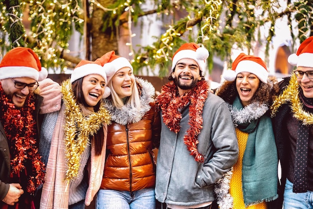 Foto grupo de jóvenes caminando alrededor de las decoraciones del árbol de navidad