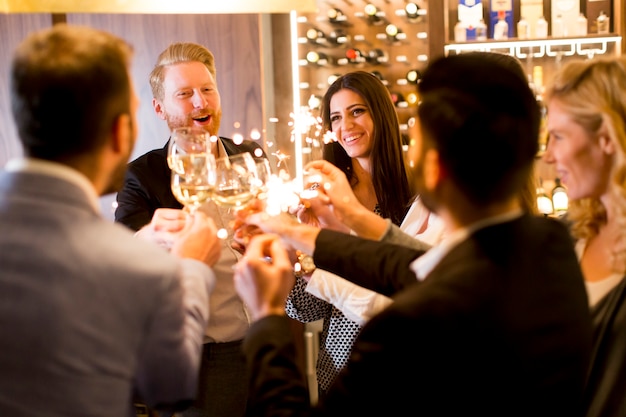 Grupo de jóvenes celebrando y brindando con vino blanco