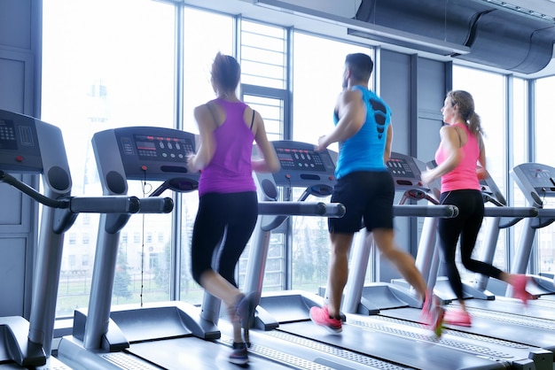 grupo de jóvenes corriendo en cintas de correr en el moderno gimnasio deportivo