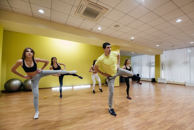 Un grupo de jóvenes deportistas realizan ejercicios en el gimnasio bajo la guía de un entrenador. Estilo de vida saludable