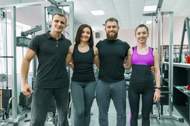 Grupo de jóvenes deportistas sonrientes abrazando juntos