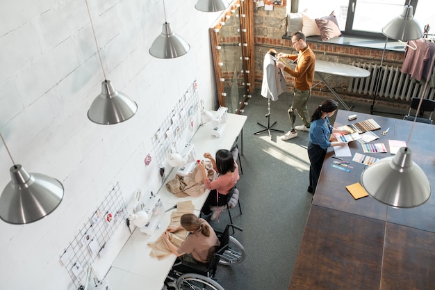 Grupo de jóvenes diseñadores de moda contemporánea y sastres que realizan un trabajo individual sobre la nueva colección de temporada en el taller