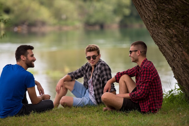 Grupo de jóvenes disfrutando de la naturaleza sentados en la orilla del río.