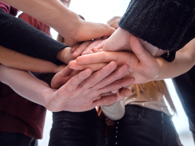 Grupo de jóvenes diversos haciendo una torre de sus manos