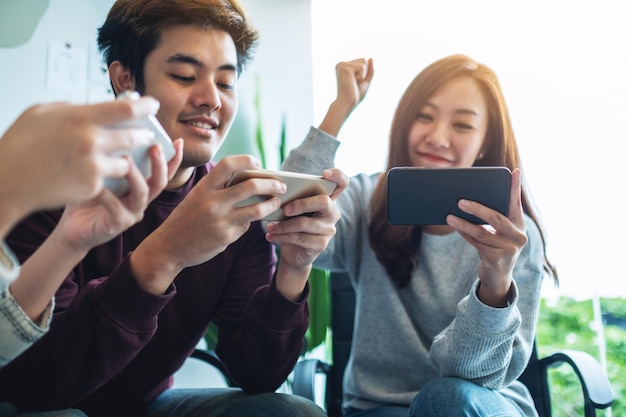 Un grupo de jóvenes divirtiéndose y celebrando mientras ven y juegan juntos en el teléfono móvil