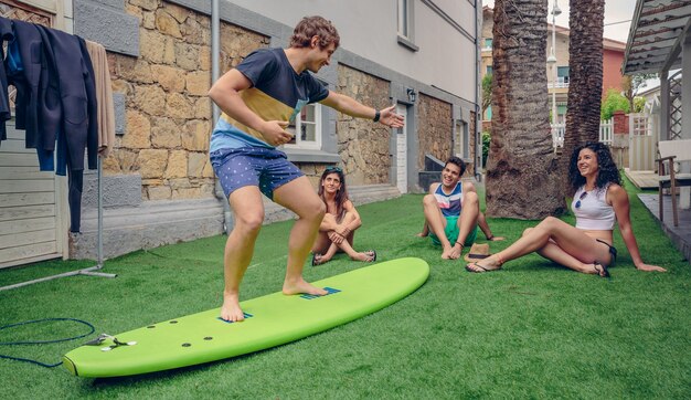 Grupo de jóvenes divirtiéndose en una clase de surf de verano al aire libre. Concepto de ocio de vacaciones.