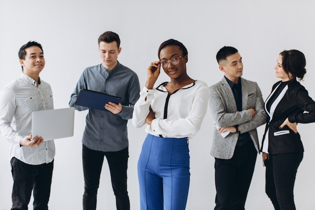 Grupo de jóvenes ejecutivos multiculturales de pie y ocupados usando teléfonos inteligentes para trabajar en la oficina. Tecnología de redes sociales y negocios en línea con concepto de estilo de vida adolescente