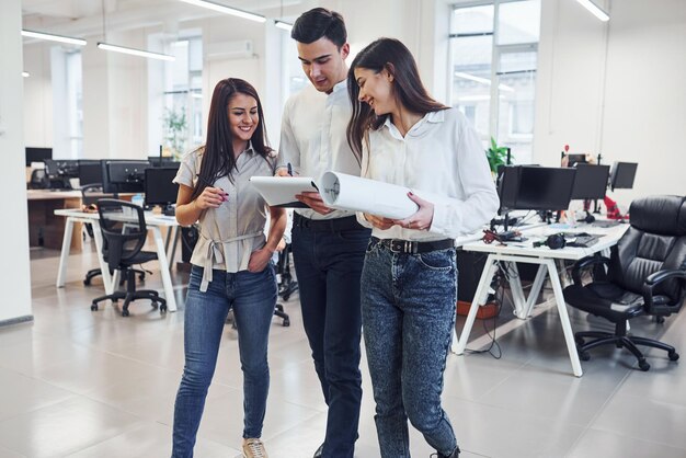 Grupo de jóvenes empleados hablando y trabajando en un nuevo proyecto en la oficina.