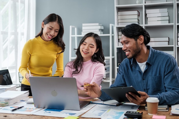 Un grupo de jóvenes empresarios asiáticos haciendo una tormenta de ideas mirando una computadora portátil