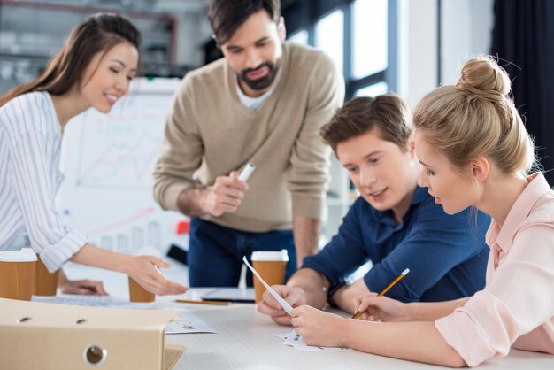 Grupo de jóvenes empresarios discutiendo el nuevo plan de negocios en la reunión