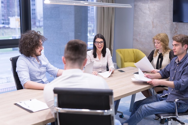 Grupo de jóvenes empresarios discutiendo plan de negocios en el edificio de oficinas de inicio moderno