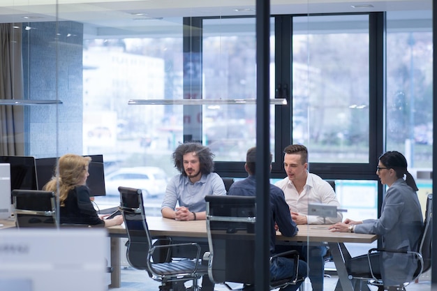 Grupo de jóvenes empresarios discutiendo plan de negocios en el edificio de oficinas de inicio moderno