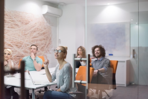 Grupo de jóvenes empresarios discutiendo el plan de negocios en el moderno edificio de oficinas de inicio nocturno