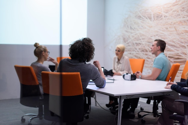 Grupo de jóvenes empresarios discutiendo el plan de negocios en el moderno edificio de oficinas de inicio nocturno