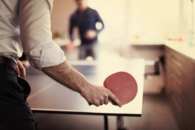 Grupo de jóvenes empresarios de inicio jugando tenis de ping pong en la moderna oficina creativa