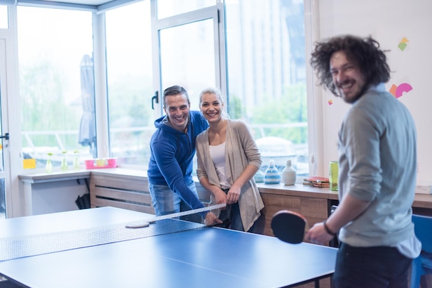Grupo de jóvenes empresarios de inicio jugando tenis de ping pong en la moderna oficina creativa