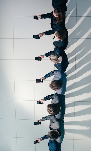 Grupo de jóvenes empresarios mirando las pantallas de sus teléfonos inteligentes