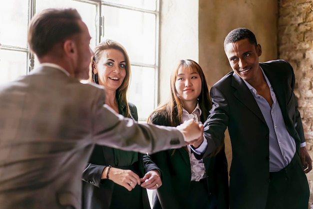 Un grupo de jóvenes empresarios multiétnicos dándose la mano durante un negocio en funcionamiento