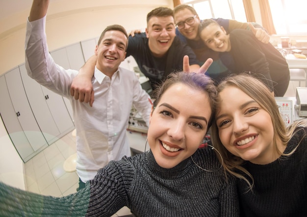 grupo de jóvenes estudiantes felices haciendo una foto selfie usando un teléfono inteligente después de un día exitoso en el aula de electrónica