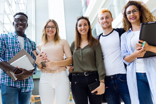 Grupo de jóvenes estudiantes felices mirando la cámara en una universidad.