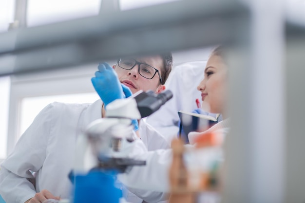 Grupo de jóvenes estudiantes de medicina investigando juntos en el laboratorio de química, trabajo en equipo de estudiantes universitarios en el interior