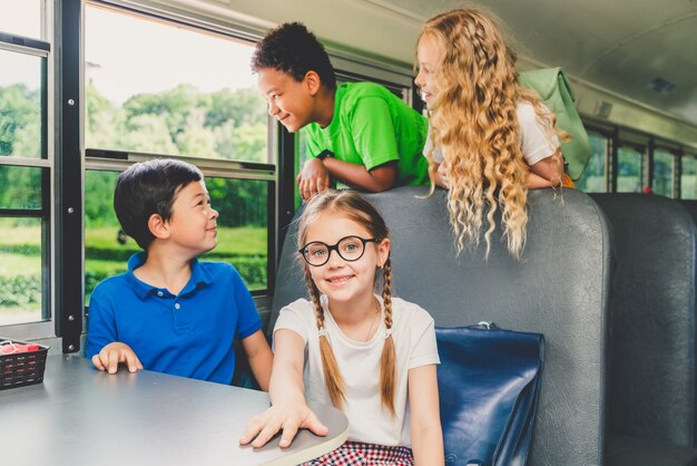 Grupo de jóvenes estudiantes que asisten a la escuela primaria en un autobús escolar amarillo - Los niños de la escuela primaria se divierten