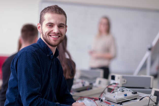 Grupo de jóvenes estudiantes que realizan prácticas técnicas vocacionales con maestros en el aula electrónica, concepto de educación y tecnología