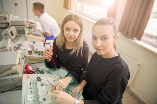 Grupo de jóvenes estudiantes que realizan prácticas técnicas vocacionales con maestros en el aula electrónica, concepto de educación y tecnología