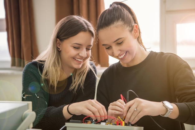 Grupo de jóvenes estudiantes que realizan prácticas técnicas vocacionales con maestros en el aula electrónica, concepto de educación y tecnología