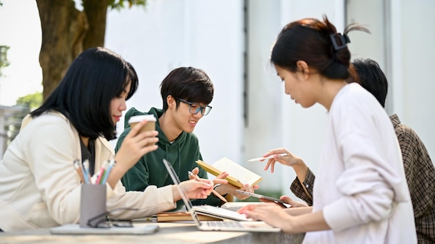 Grupo de jóvenes estudiantes universitarios dando tutoría y preparándose para el examen en un parque del campus