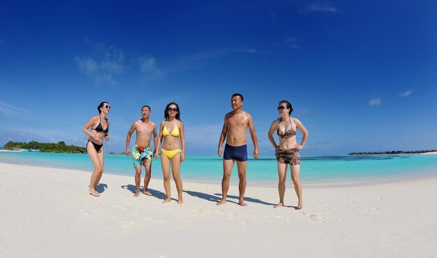 un grupo de jóvenes felices se divierten y se alegran en la playa de arena blanca en un hermoso día de verano