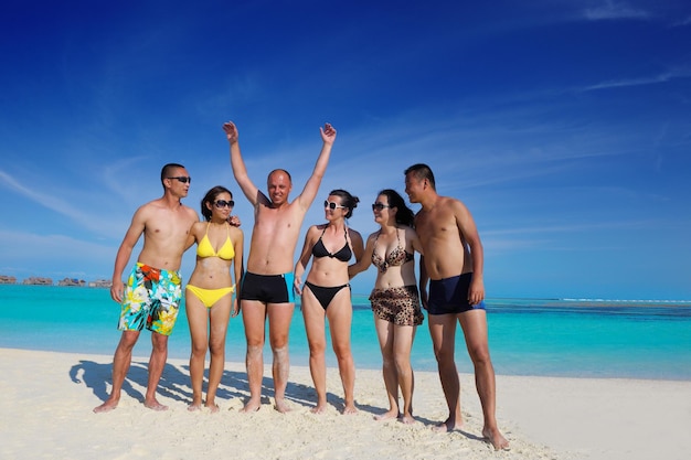 un grupo de jóvenes felices se divierten y se alegran en la playa de arena blanca en un hermoso día de verano