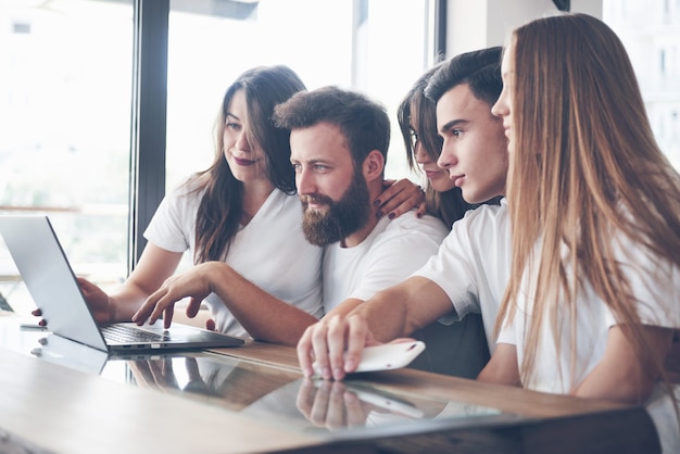 Un grupo de jóvenes con gadgets y una computadora portátil organizan una lluvia de ideas y se comunican entre sí. El concepto de desarrollar una empresa joven.