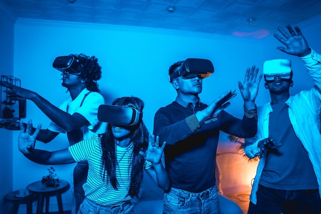 Grupo de jóvenes en gafas vr en un juego de realidad virtual en una luz azul asombrado tocando objetos virtuales futuristas o concepto de tecnología científica