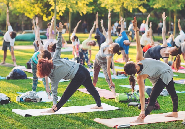 Un grupo de jóvenes hace yoga en el parque al atardecer.