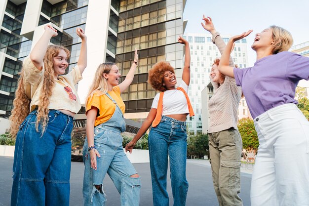 Grupo de jóvenes locas felices bailando con música y divirtiéndose en una reunión social en la ciudad